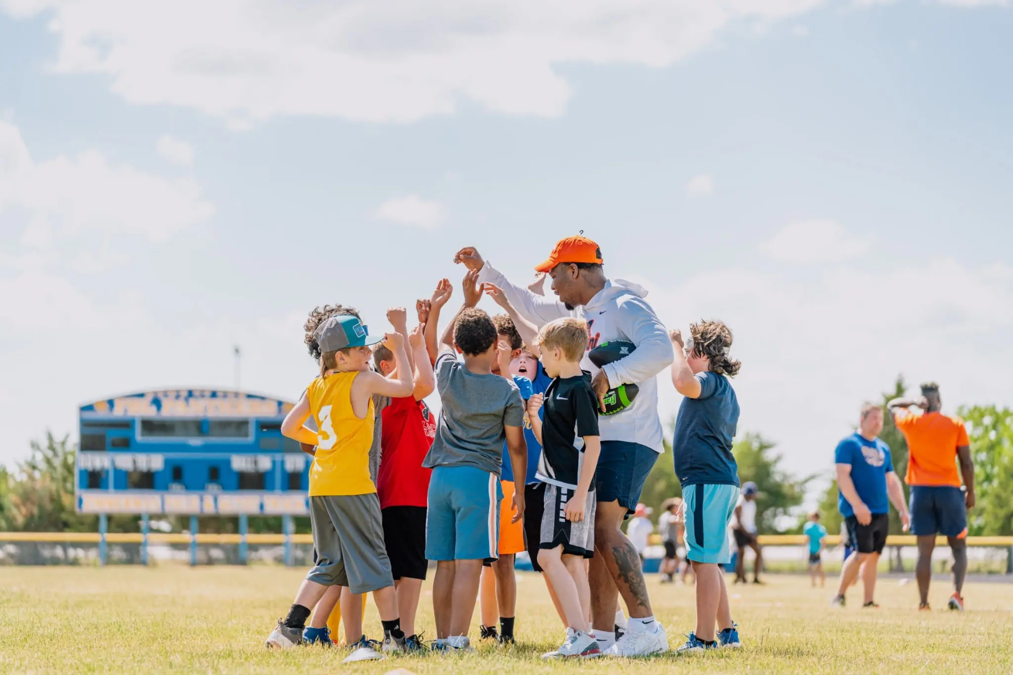 A college athlete leading a team huddle with young players at a Top Tier camp